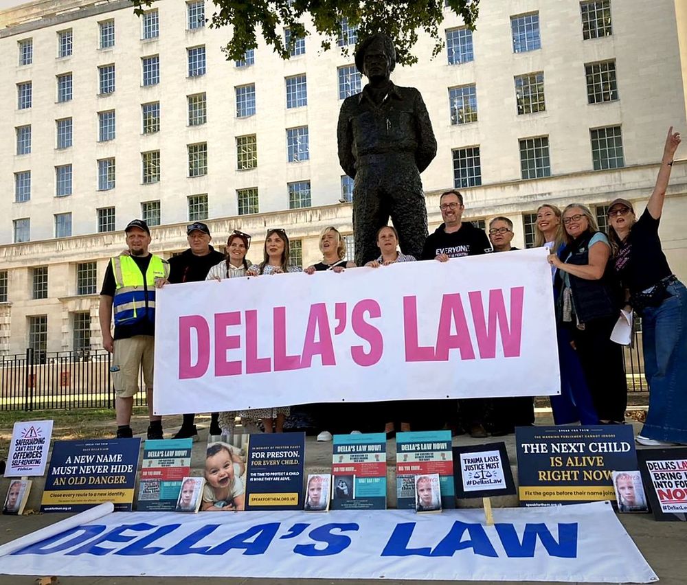 Campaigners holding a Della's Law banner on Whitehall, with Speak For Them and Della's Law placards laid out in front of them.